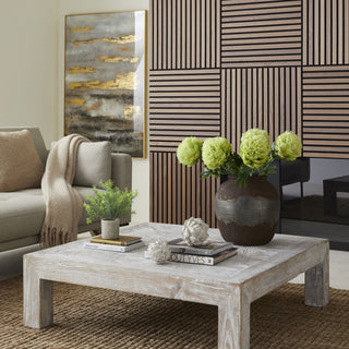 Rosemary plant displayed on a coffee table next to a grey sofa and wood slatted wall.