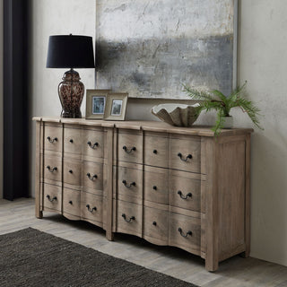 Pair of rustic whitewashed wooden frames displayed on a wooden chest of drawers, next to a dark lamp and abstract artwork.