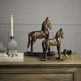 Two rustic wooden rocking horses, large and small, displayed on a wooden chest.