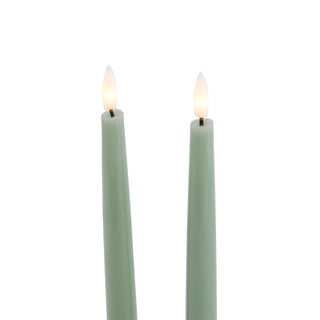 Close detail of the illuminated LED flame tips on the two sage green dinner candles.