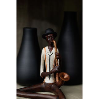 Detail shot showing the figurine's hat, facial features, and shirt with braces, framed by two tall black vases.