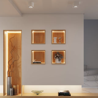 Modern interior showing two square ceramic spotlights illuminating a white wall with recessed wooden shelving.