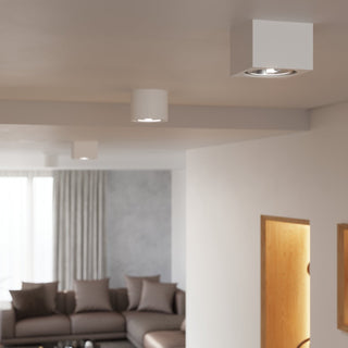 Square ceramic and cylindrical ceiling fixtures used together in a neutral-toned open-plan room.