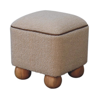 Square footstool in beige boucle fabric with brown piping, supported by four smooth wooden ball feet.