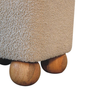 Close detail of the beige boucle fabric texture and two smooth wooden ball feet.