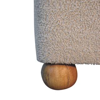 Close detail of the beige boucle upholstery texture resting directly on one wooden ball foot.