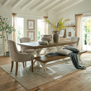 Siena brown amphora pot used as a vase, holding foliage on a wooden dining table in a neutral dining room.