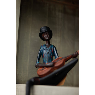 Close-up of the figurine's face wearing a black bowler hat, smiling while playing the wooden guitar.