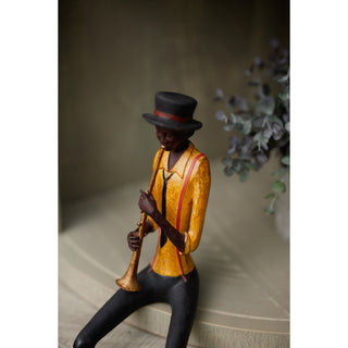 Close-up showing the figurine's top hat, yellow shirt, and hands holding the brass instrument.