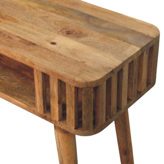 Close detail of the wooden console showing the grain, rounded corner, slatted side panel, and the start of a tapered leg.