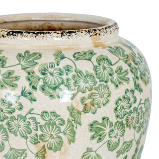 Detail shot of the cream vase with green clover pattern, crackled surface, and aged, dark rim.