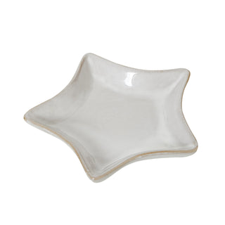 White ceramic four-pointed star dish, slightly angled, showing the glossy interior and contrasting rustic edge.