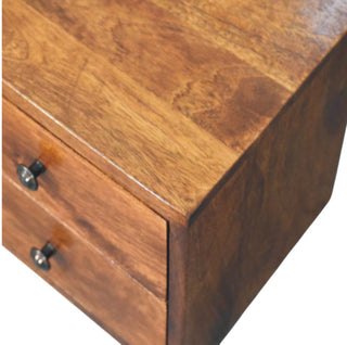 Close-up detail of the chestnut nightstand showing the corner joint, wood grain, and top edge above the drawers.