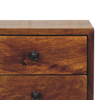 Detail shot of the rich chestnut wood grain, polished top edge, and dark metal drawer handles.