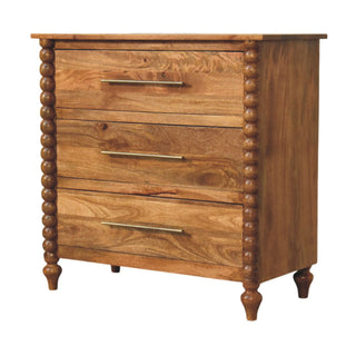 Angled view of the three-drawer mango wood chest highlighting the wood grain and the bobble spindle side columns.