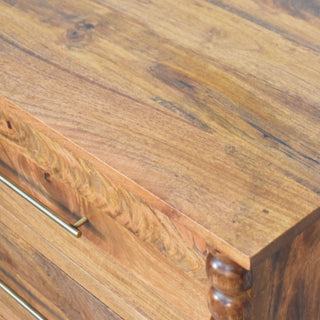 Close-up of the mango wood chest top surface, brass handle, and the upper section of the bobble spindle.