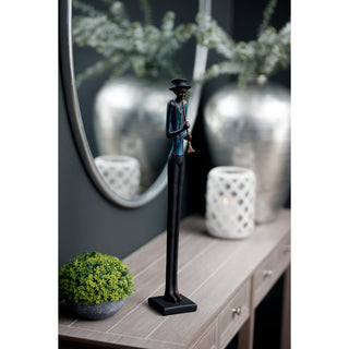 Figurine displayed on a wooden console table next to a potted plant, with a mirror behind.