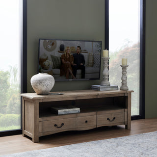 Stone ceramic vase displayed on a light wood TV console next to two tall white candle holders in a living room.
