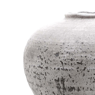 Close detail of the rough, stone-effect texture and the curved shoulder of the ceramic vase.