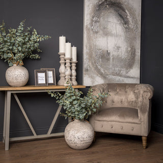 Two large spherical stone vases styled in a dark corner room setting with a beige armchair.