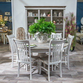 Aged stone effect vase used as a centrepiece on a round dining table, filled with large green fern foliage.