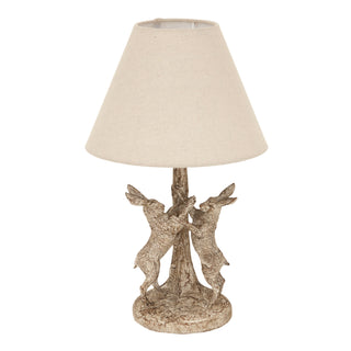 Table lamp with a stonewashed base depicting two hares and a plain conical linen shade.
