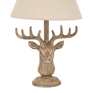 Close-up detail of the stonewashed stag head base showing the texture and the linen shade above.