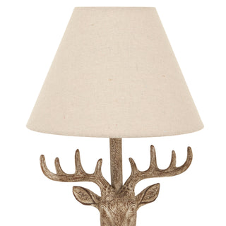 Tight crop showing the conical linen shade texture above the stag head antlers.