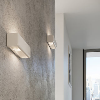 Pair of illuminated ceramic wall lights mounted horizontally on a textured wall in a modern interior.