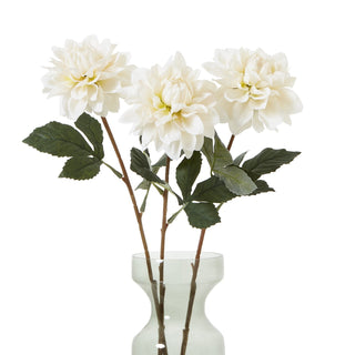 Three artificial white dahlia stems arranged in a pale green glass vase against a white background.
