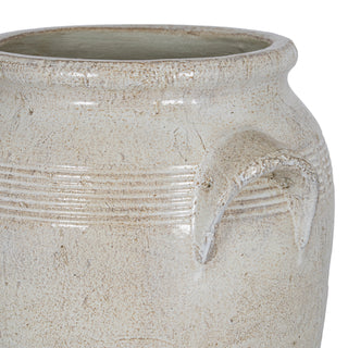 Close detail of the textured off-white ceramic pot, highlighting the rolled rim and the loop handle attachment.