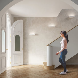 Three wall lamps mounted in a hallway with a staircase, showing rectangular and curved designs.