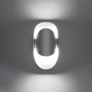 Close view of the lit wall lamp showing the pools of light cast onto the wall surface.
