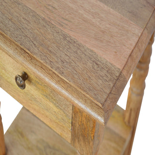 Detail of the wooden tabletop, drawer front, and antique brass pull, highlighting the corner joint.