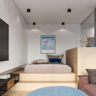 Four black cylindrical lights illuminating a raised bed platform in a compact modern room.