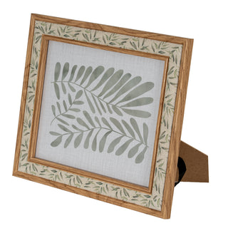 Angled view of the wood-effect frame, highlighting the fabric mount with small border leaves and large central leaves.