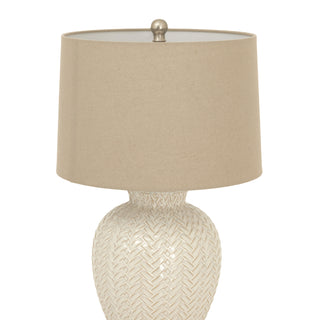 Upper section of the lamp, showing the cylindrical beige shade and the silver-toned finial against a white background.