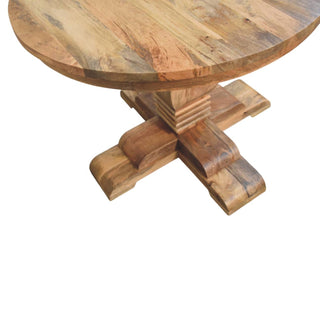 Angled detail of the stepped pedestal base and the thick, curved profile of the table's cross feet.