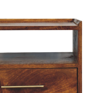 Close-up detail of the bedside table's top surface, open shelf, and drawer showing the rich wood finish.