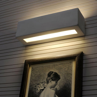 Ceramic wall lamp mounted above a framed picture on a slatted wall, providing downward accent lighting.