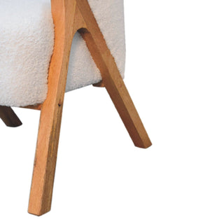 Detail of the angled wooden legs and the base joint with the white boucle upholstery.
