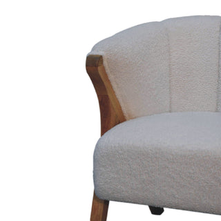Detail shot of the chair's curved corner, showing the boucle upholstery, vertical stitching, and exposed timber frame.