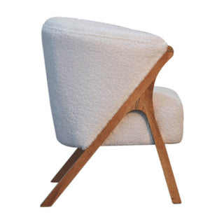 Full side profile of the white boucle chair, showing the deep curved backrest and the angled wooden A-frame support.