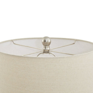 Detail of the neutral fabric shade and the brushed metal finial securing the top.