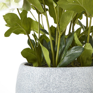 Close-up of the textured grey planter rim and artificial green stems emerging from the base.