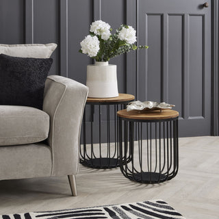 Faux white hydrangea arrangement in a vase on a side table next to a beige sofa in a dark grey room.