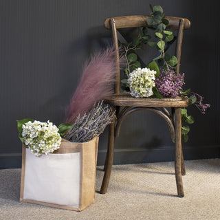 Artificial white hydrangea heads styled on a wooden chair and in a jute bag with lavender and pink pampas grass.