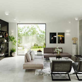 White cubic wall light installed in a modern living room setting, illuminating artwork on a white wall.