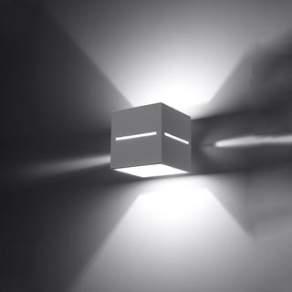 White cubic wall light showing multi-directional illumination patterns on the surrounding wall surface.