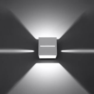 White cubic wall light showing six symmetrical beams of light projecting onto the wall surface.